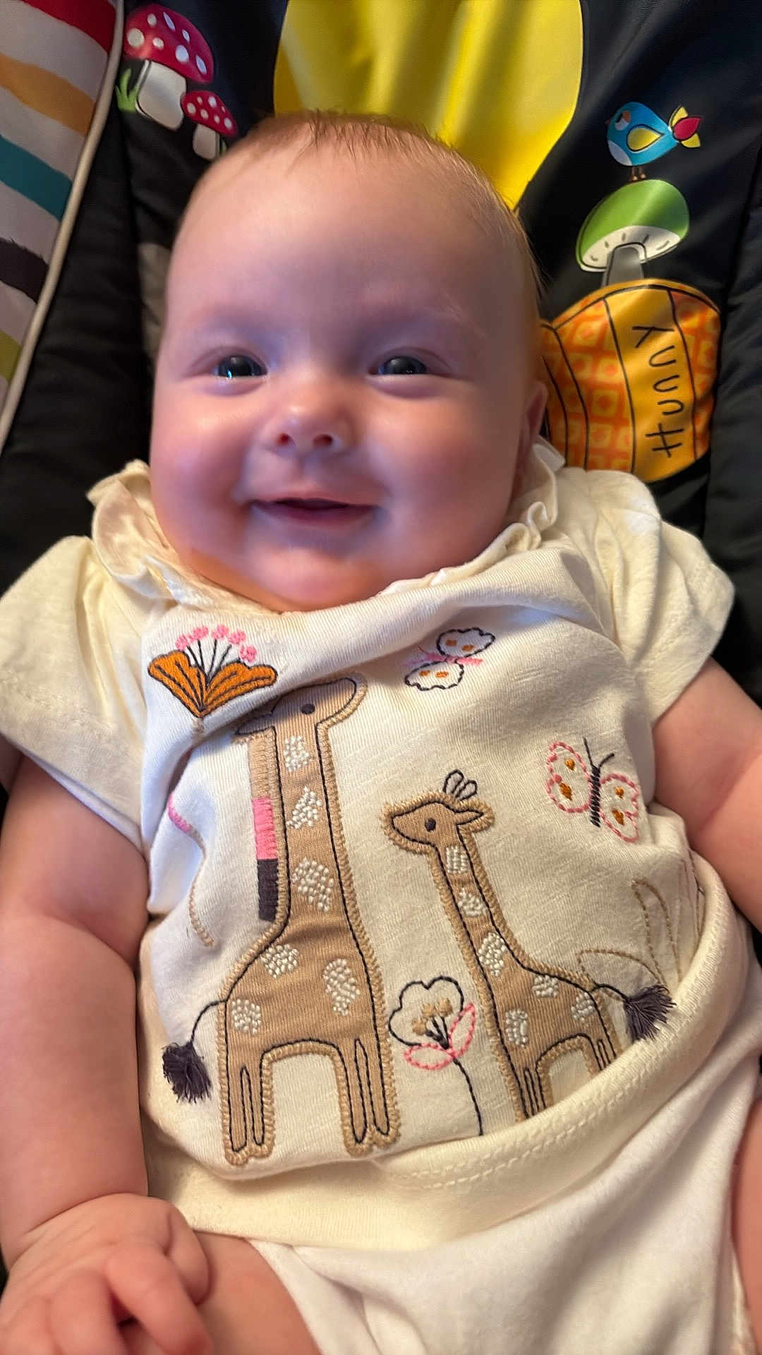 Maliyah joined the competition — help win amazing prizes! baby, smiling, infant, cute, giraffe, embroidered_clothing, butterfly, patterned_background, child, sitting, closeup, happy, cute_clothing, soft_lighting, indoor, person, head, face, arm, hand