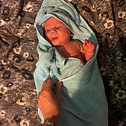 Austin is registered to the contest to win money with this photo: baby, towel, hand, blanket, infant, wrapped, bed, pattern, soft, cozy, cute, newborn, skin, person, lying_down, blue, warm, comfort, small, expression