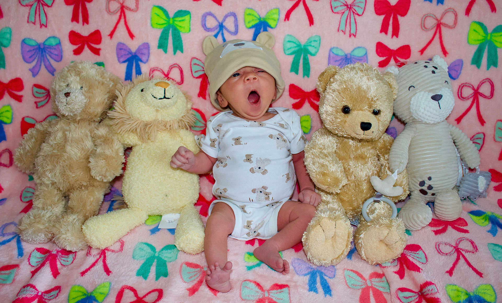 Keonna Marie is registered to the contest to win money with this photo: baby, infant, yawning, hat, onesie, stuffed_animals, teddy_bear, lion_toy, blanket, colorful, bows, plush, cute, child, indoor, soft_toys, sitting, adorable, cozy, portrait