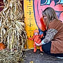 baby, woman, pumpkin, corn_stalks, hay, height_chart, orange_outfit, hat, autumn, fall, smile, wood_floor, leaf, measuring_scale, outdoor, seasonal, costume, holding, child, portrait