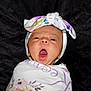 baby, infant, yawn, headwrap, blanket, floral_pattern, wrapped, cute, sleepy, portrait, child, newborn, soft, expression, face, person, indoors, closeup, black_background, adorable