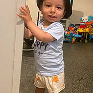 Kelio Leonard a rejoint le concours — aidez-le/la à gagner de superbes lots ! toddler, child, hat, bucket_hat, shirt, shorts, sandals, indoor, toys, playroom, smile, standing, door_frame, happy, person, footwear, colorful, floor, expression, casual