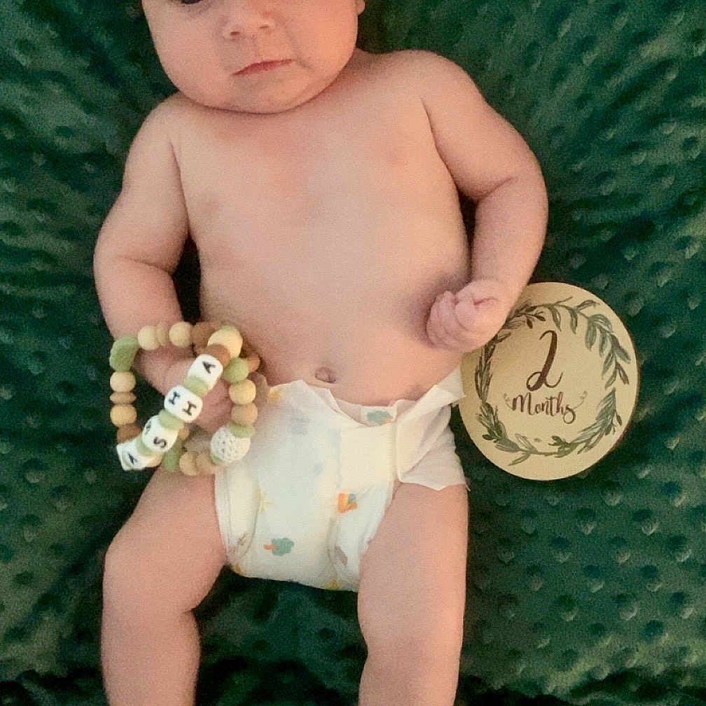 Sasha participe au concours pour gagner de l'argent avec cette photo : baby, bracelet, child, cute, decorative, diaper, expression, face, foot, green_blanket, hand, head, infant, lying_down, milestone, newborn, person, skin, two_months, wooden_sign