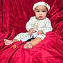Dante is registered to the contest to win money with this photo: baby, infant, child, christmas_hat, red_blanket, blanket, controller, video_game_controller, pacifier, bare_feet, sitting, portrait, onesie, holiday, cozy, indoors, cute, expression, toy, face
