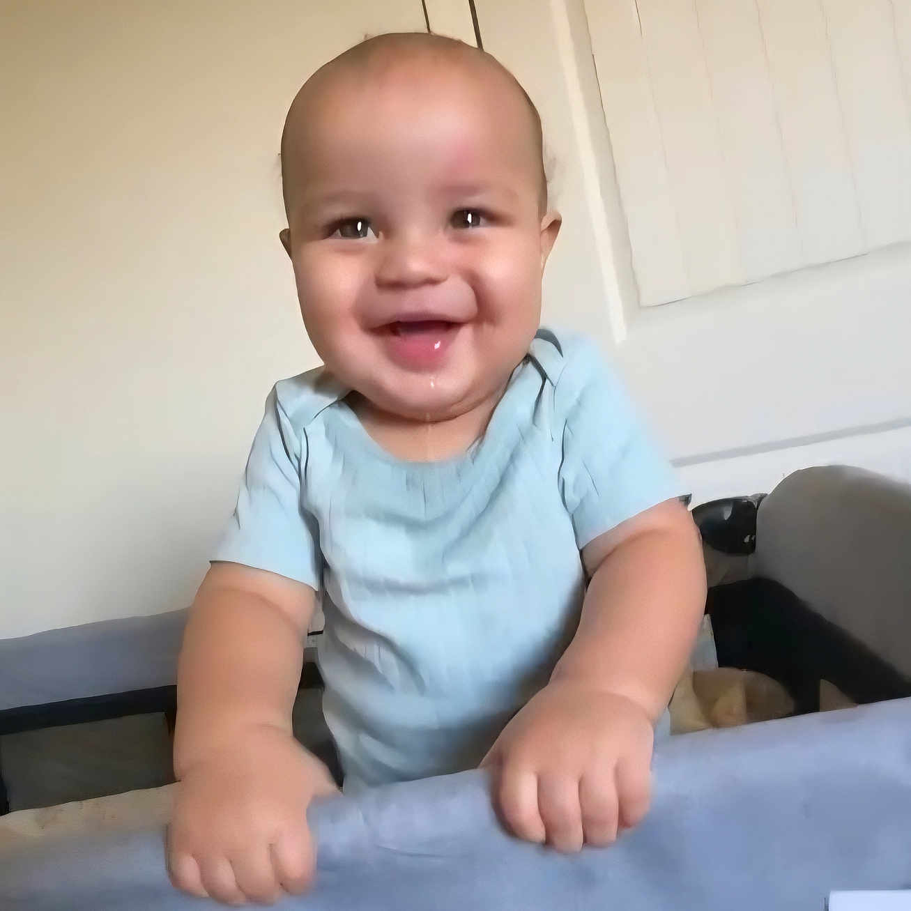 Dante is registered to the contest to win money with this photo: baby, bald, blinds, chubby_cheeks, crib, cute, door, drooling, face, hands, happy, home, indoor, infant, onesie, playpen, portrait, smiling, standing, wall