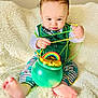 Merrick joined the competition — help win amazing prizes! baby, infant, child, beads, pot_of_gold, rainbow, blanket, sitting, playing, green_clothing, striped_pants, barefoot, portrait, closeup, indoor, soft_texture, curious, festive, toy, hands