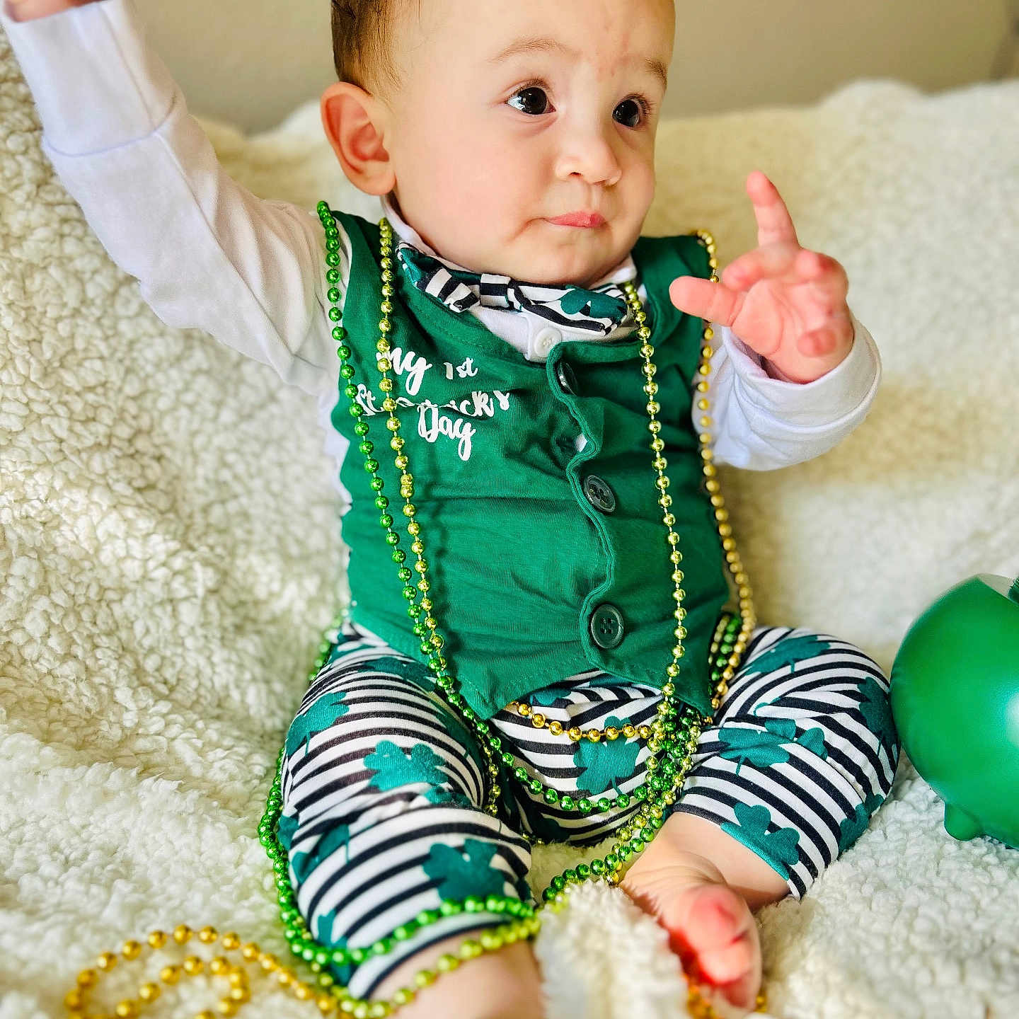 Merrick joined the competition — help win amazing prizes! baby, beads, blanket, bow_tie, celebration, child, close_up, curious_expression, cute, face, festive, green_clothing, indoor, infant, portrait, shamrock, sitting, st_patricks_day, striped_pants, toy