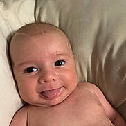 Woodrow is registered to the contest to win money with this photo: baby, tongue, smile, face, skin, head, eyes, pillow, cheek, infant, expression, cute, playful, lying_down, bare_chest, child, closeup, human, adorable, happy