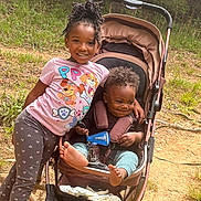 Ever is registered to the contest to win money with this photo: child, baby, stroller, outdoor, forest, smiling, girl, infant, nature, happy, clothing, footwear, grass, family, cute, toddler, playful, leisure, sunlight, trees