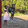 Ever is registered to the contest to win money with this photo: child, children, swing, playground, park, smiling, happy, outdoor, greenery, sunlight, grass, woodchips, summer, dress, shorts, sandals, fun, play, person, nature