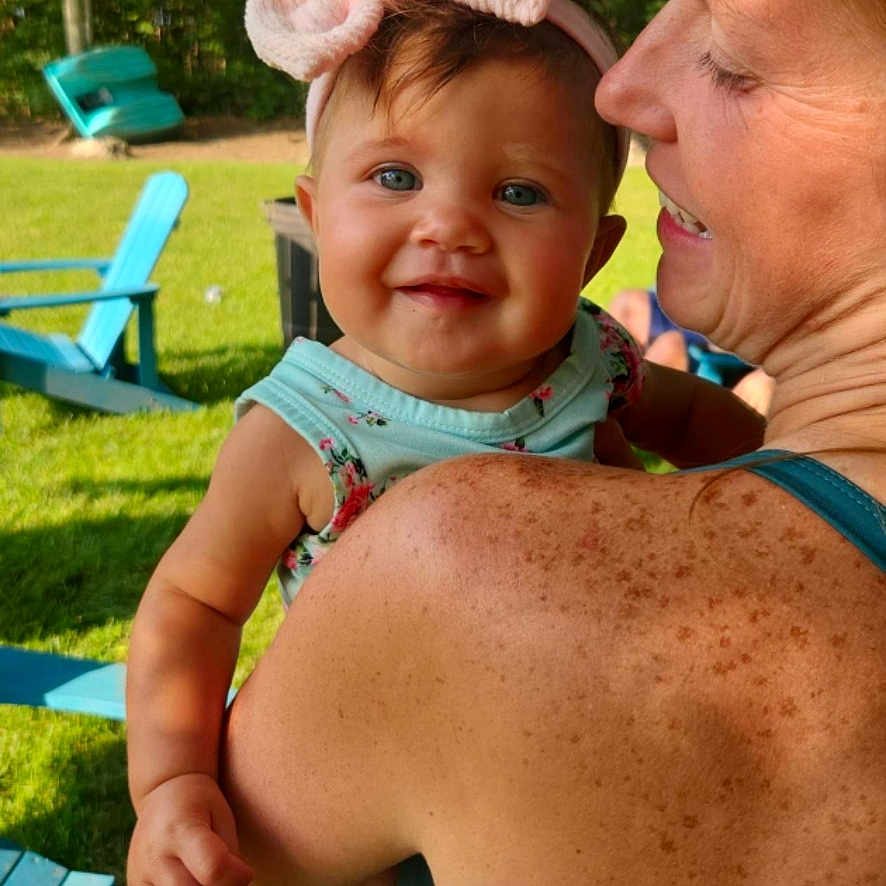 Loretta joined the competition — help win amazing prizes! baby, blue_eyes, casual_clothing, chair, child, family, freckles, grass, greenery, happy, headband, outdoor, pink_bow, portrait, shoulder, smile, summer, sunlight, trees, woman
