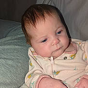 Jade is registered to the contest to win money with this photo: baby, infant, face, hand, blanket, clothing, onesie, couch, pillow, soft, indoor, child, cute, portrait, skin, expression, sitting, young, person, cozy