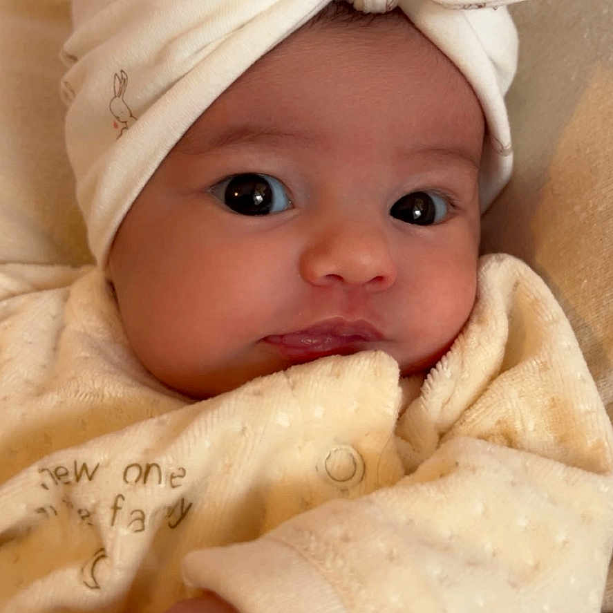 Anavy a rejoint le concours — aidez-le/la à gagner de superbes lots ! adorable, baby, bow, child, closeup, clothing, cream_color, cute, expression, face, hand, head_wrap, indoor, infant, newborn, person, portrait, skin, sleepwear, soft_texture