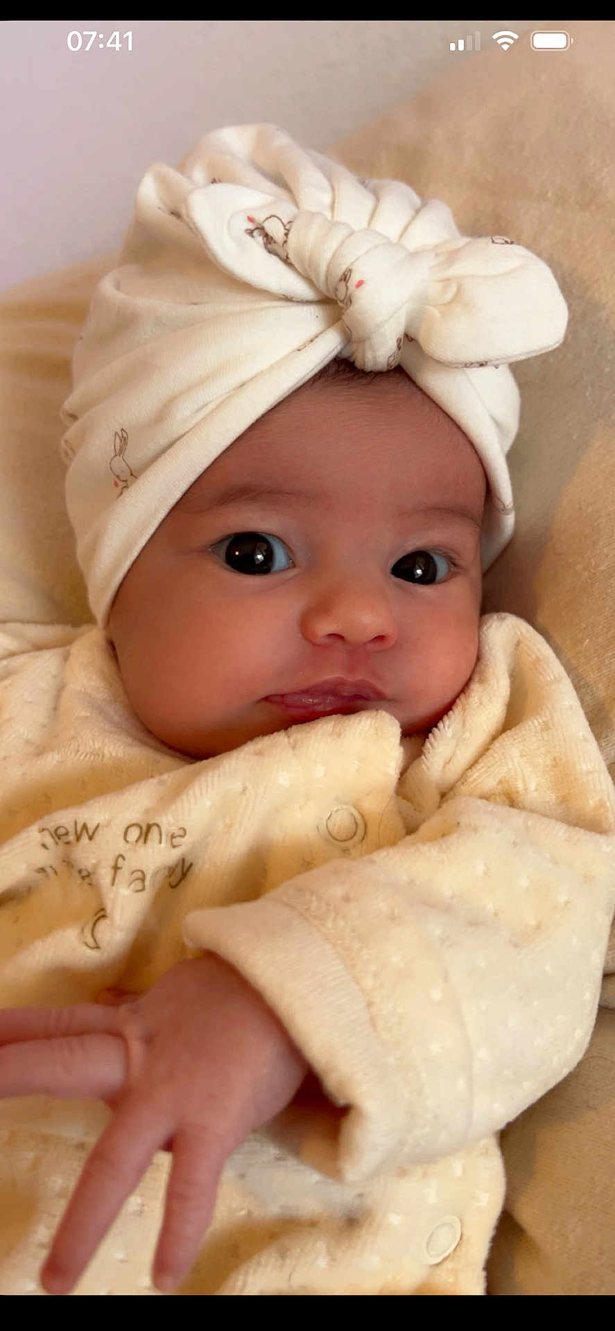 Anavy a rejoint le concours — aidez-le/la à gagner de superbes lots ! baby, infant, face, head_wrap, bow, hand, clothing, cream_color, cute, portrait, newborn, soft_texture, indoor, closeup, expression, child, adorable, skin, person, sleepwear