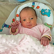 Espérance participe au concours pour gagner de l'argent avec cette photo : baby, newborn, infant, blanket, pink_blanket, onesie, baby_seat, cushion, dinosaur_print, hand, face, eyes, indoors, portrait, cozy, awake, soft_texture, bedding, head, adorable