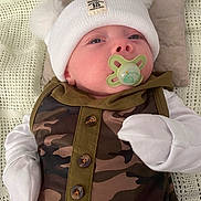 Alexander joined the competition — help win amazing prizes! baby, pacifier, hat, mittens, camo_clothing, blanket, pillow, infant, face, person, newborn, cute, sleepy, comfort, soft, resting, indoor, portrait, headwear, child
