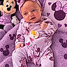 Arizona joined the competition — help win amazing prizes! baby, infant, child, portrait, lying_down, smiling, headband, bow, pajamas, pink, purple, minnie_mouse, stuffed_toy, pacifier, blanket, pillow, nursery, indoors, close_up, happy