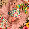 Arizona is registered to the contest to win money with this photo: baby, infant, child, girl, smiling, lying_down, portrait, floral, flowers, pink_blanket, colorful_clothing, dress, toy, caterpillar_toy, wooden_sign, nursery, outdoor_inspired, happy, close_up, photography