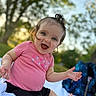 Everlee is registered to the contest to win money with this photo: baby, child, smiling, outdoor, grass, blanket, happy, person, cute, blue_eyes, pink_shirt, black_shorts, nature, daylight, portrait, sitting, young_child, sunlight, trees, joy