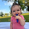 Everlee is registered to the contest to win money with this photo: toddler, child, baby, outdoor, grass, blue_sky, toy, pink_shirt, black_shorts, smiling, happy, sitting, face, hand, cute, nature, daylight, playing, park, portrait