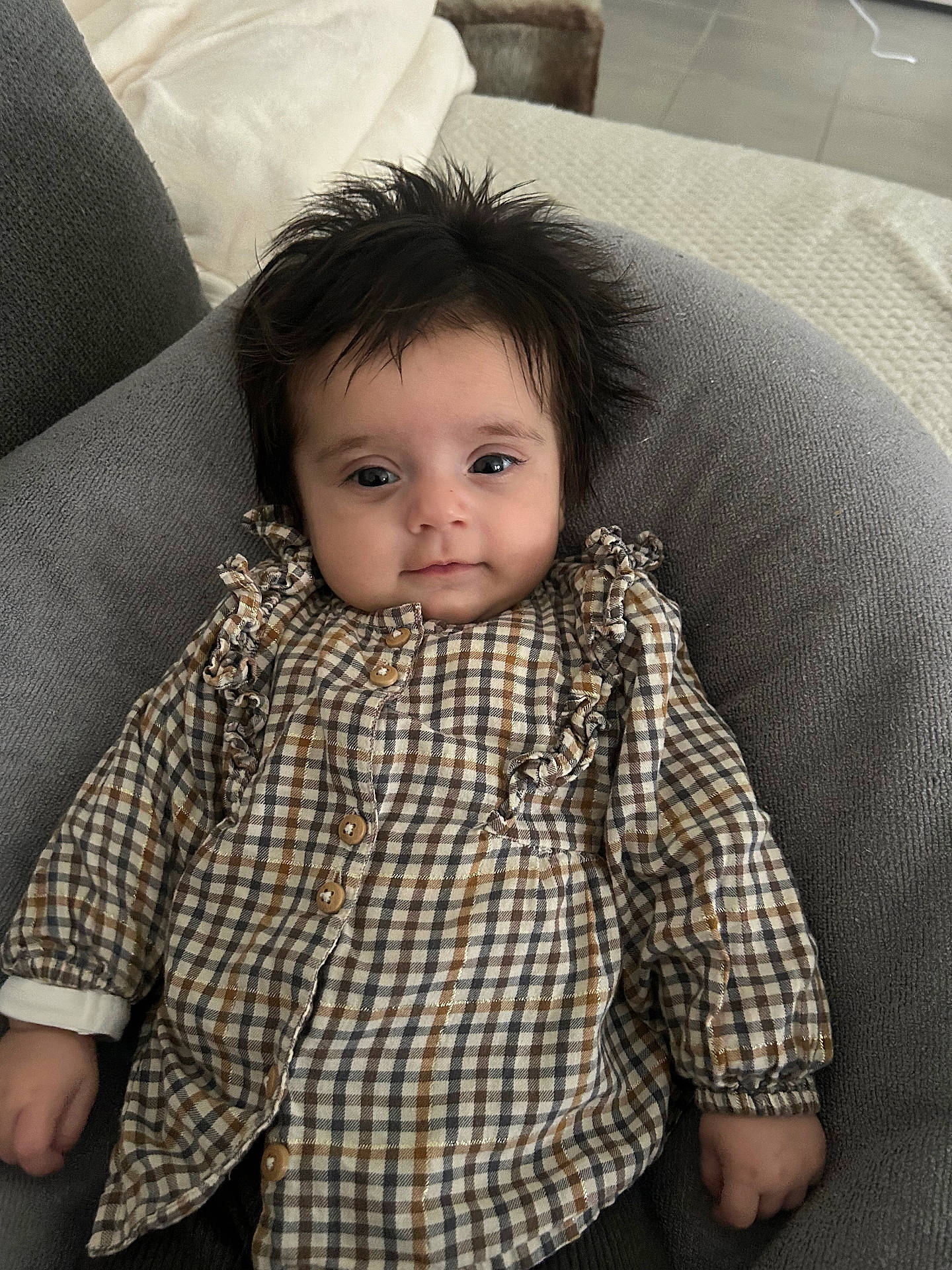 Sofia participe au concours pour gagner de l'argent avec cette photo : baby, buttoned_shirt, checkered_shirt, child, clothing, cushion, cute, expression, eyes, face, furniture, gray, hair, hand, indoor, infant, person, portrait, sitting, young