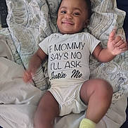 Nya'Lease is registered to the contest to win money with this photo: baby, child, smiling, onesie, clothing, blanket, pattern, lying_down, indoors, happy, thumbs_up, sock, cute, infant, person, face, expression, relaxed, toddler, home