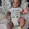 baby, child, smiling, onesie, clothing, blanket, pattern, lying_down, indoors, happy, thumbs_up, sock, cute, infant, person, face, expression, relaxed, toddler, home