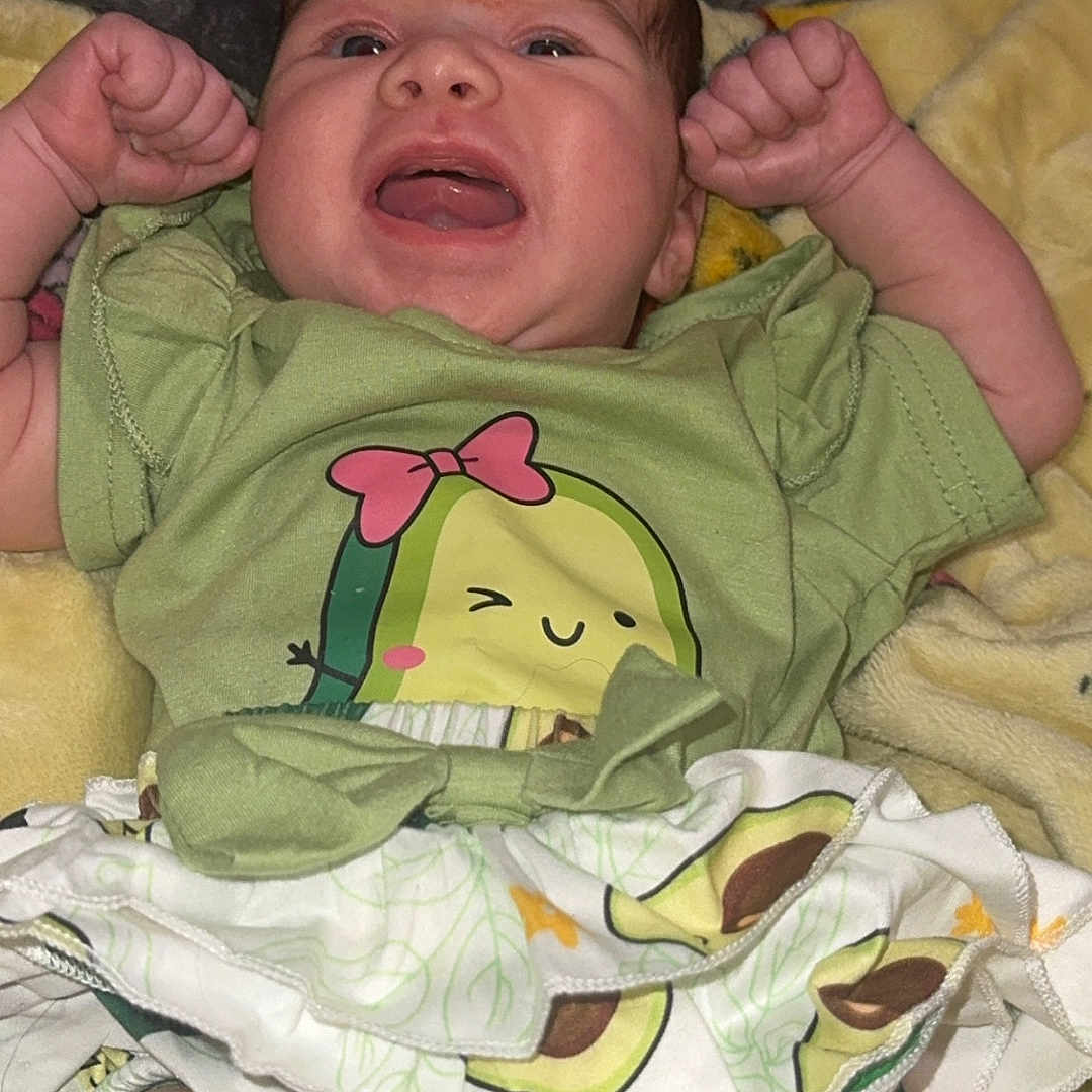 Xylin joined the competition — help win amazing prizes! baby, infant, cute, green_shirt, avocado_print, skirt, blanket, lying_down, expression, arms_up, chubby_legs, clothing, toddler, indoor, person, face, skin, happy, cute_outfit, child
