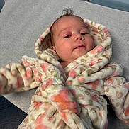 Xylin joined the competition — help win amazing prizes! baby, infant, child, face, portrait, blanket, swaddled, cozy, lying_down, indoors, nursery, soft_blanket, floral_pattern, pastel_colors, looking_at_camera, dark_hair, blue_wall, photography, adorable, newborn