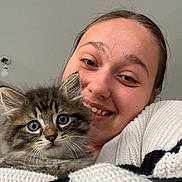 Scar participe au concours pour gagner de l'argent avec cette photo : person, cat, kitten, smiling, face, furry, cute, cozy, knitwear, sweater, indoor, portrait, closeup, tabby, whiskers, eyes, head, snuggling, happy, pet