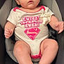 Nakyshia is registered to the contest to win money with this photo: baby, child, infant, car_seat, onesie, pacifier, cute, supergirl, pink, white_clothing, sitting, safety, child_seat, young_child, adorable, face, legs, arms, foot, expression