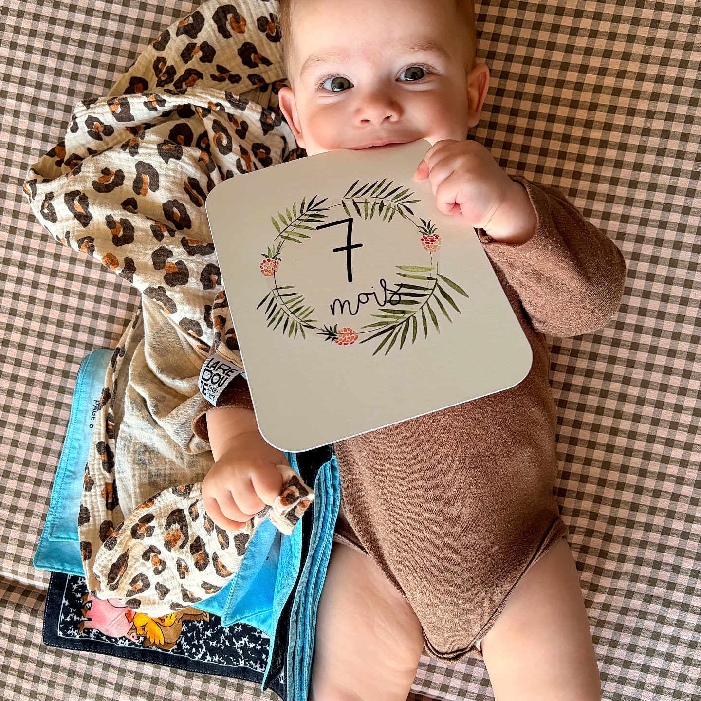 James a rejoint le concours — aidez-le/la à gagner de superbes lots ! baby, infant, child, onesie, blanket, checkered_pattern, leopard_print, cloth, sign, hand, face, smiling, lying_down, cute, indoor, skin, eyes, mouth, head, playful