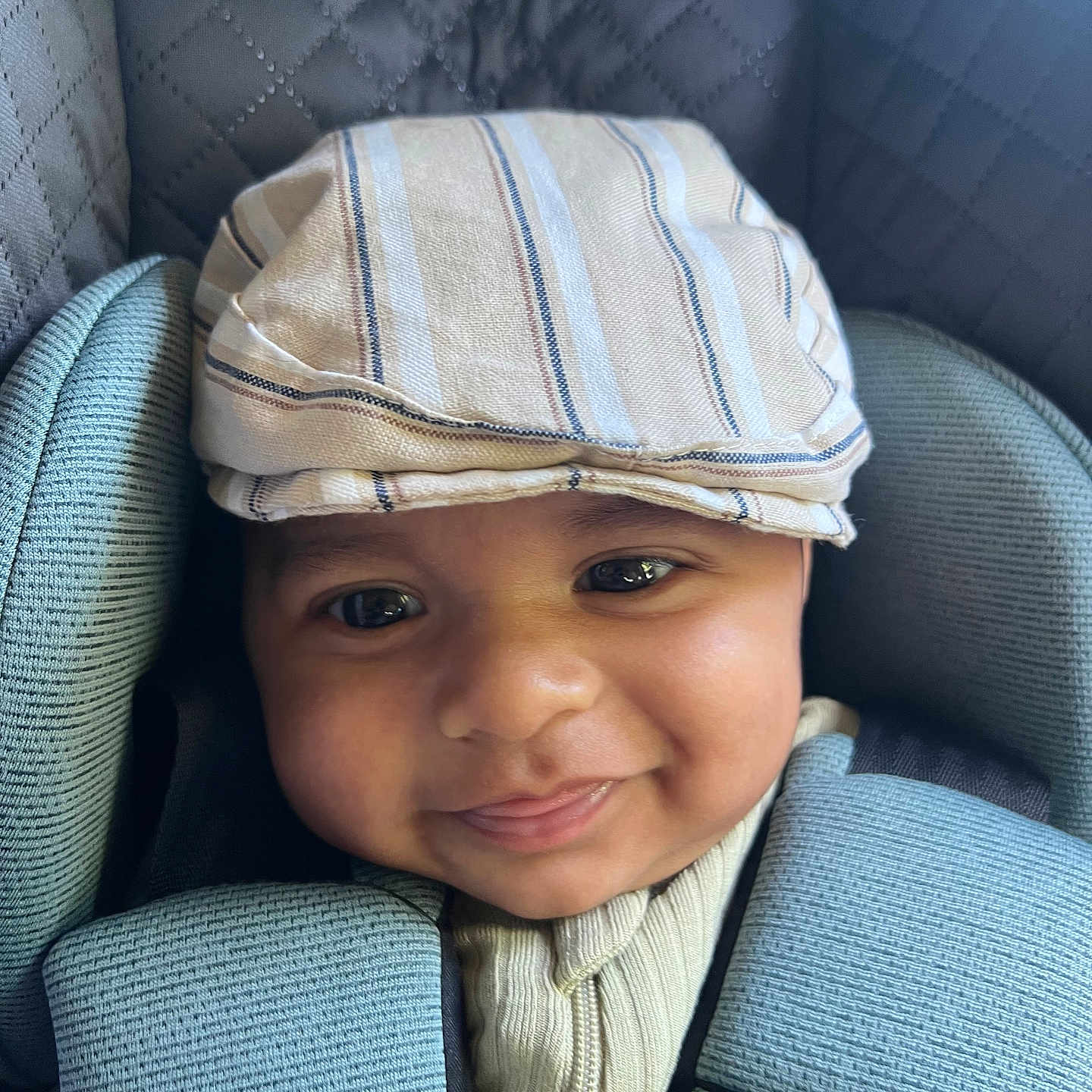 Rudra is registered to the contest to win money with this photo: baby, child, smiling, face, hat, striped_hat, car_seat, seatbelt, clothing, infant, cute, portrait, closeup, happy, headwear, fabric, textile, safety, young, person