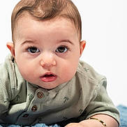 Ilyas participe au concours pour gagner de l'argent avec cette photo : arm, baby, blanket, blue_blanket, bracelet, closeup, clothing, curious, cute, eyes, face, green_shirt, hand, indoor, infant, lying_down, mouth, palm_tree_pattern, portrait, skin