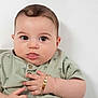 Ilyas participe au concours pour gagner de l'argent avec cette photo : baby, background, bracelet, child, chubby_cheeks, clothing, cute, expression, eyes, face, green_shirt, hand, infant, palm_tree_pattern, person, portrait, skin, studio, tongue, young