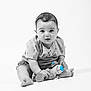Ilyas participe au concours pour gagner de l'argent avec cette photo : baby, barefoot, black_and_white, blue_accent, bracelet, child, curly_hair, cute, infant, isolated, looking_at_camera, minimalist, plush_toy, portrait, shirt, shorts, sitting, smiling, studio, toy