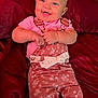 baby, smiling, infant, pink_clothing, overalls, floral_pattern, happy, cute, child, portrait, lying_down, red_blanket, indoors, skin, face, hands, blue_eyes, short_hair, button, lace_bow
