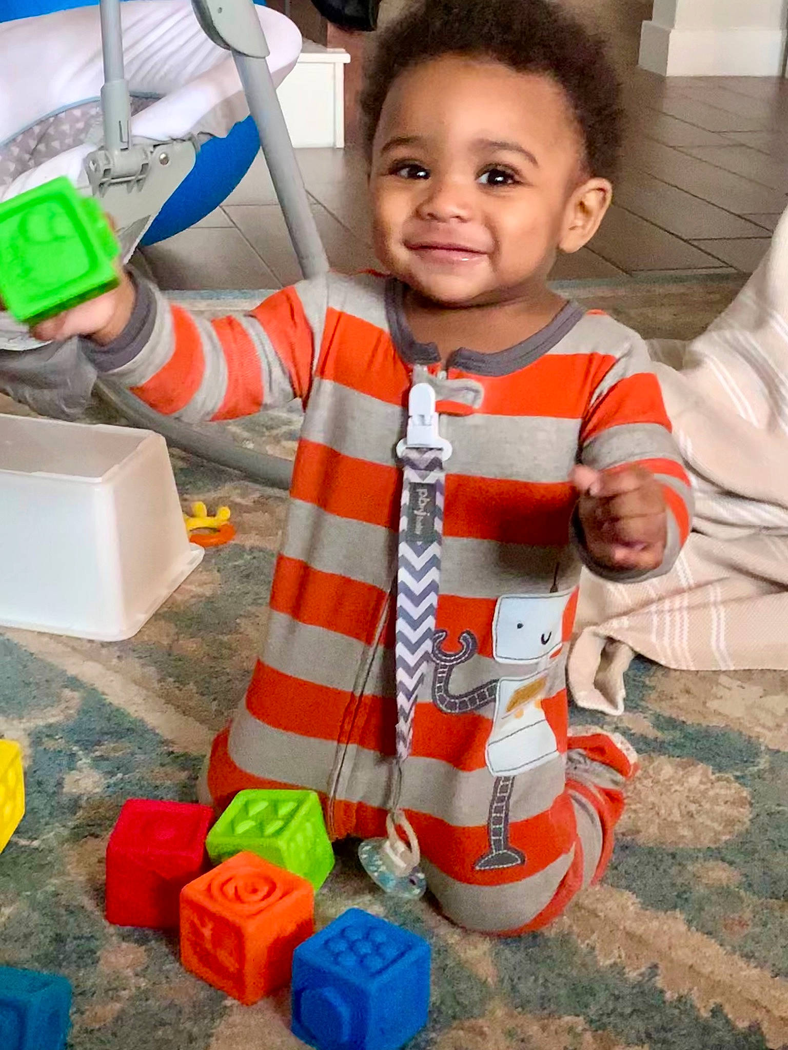 Ace is registered to the contest to win money with this photo: baby, baby_toddler_clothing, baby_toys, child, fun, green, happy, joy, orange, pattern, person, personal_protective_equipment, plastic, play, product, sleeve, smile, t_shirt, toddler, toy