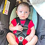 Braxton is registered to the contest to win money with this photo: baby, child, car_seat, red_onesie, straps, infant, cute, legs, toes, face, eyes, seat, cushion, pattern, indoor, sitting, young, person, closeup, comfort