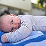 baby, infant, lying_down, blanket, quilt, gray_clothing, blue, outdoor, face, skin, head, eyes, arm, hand, soft_texture, portrait, cute, child, young, resting