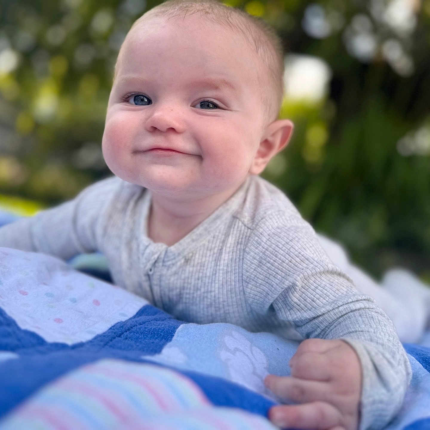 Braxton joined the competition — help win amazing prizes! baby, blanket, blue, child, crawling, cute, daylight, face, gray_clothing, greenery, hand, happy, infant, nature, outdoor, portrait, quilt, skin, smile, toddler