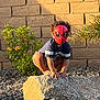 Neiko joined the competition — help win amazing prizes! child, mask, spiderman, rock, grass, plants, wall, outdoor, sunlight, curly_hair, blue_shirt, shorts, crouching, garden, backyard, nature, playful, superhero, toy, costume