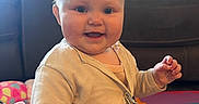 Hazel joined the competition — help win amazing prizes! baby, child, smiling, indoor, playmat, cardigan, toy, blue_eyes, face, person, sitting, foam_ring, colorful, home, couch, happy, cute, infant, play, pacifier_clip