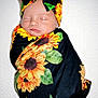 Lelanie joined the competition — help win amazing prizes! baby, black_cloth, bow, child, close_up, cute, flower_pattern, green_leaves, headband, indoor, infant, newborn, peaceful, portrait, resting, sleeping, soft_texture, sunflower, swaddle, wrapped