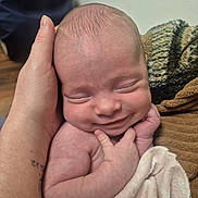 Lelanie is registered to the contest to win money with this photo: baby, newborn, smile, hand, tattoo, blanket, skin, closeup, sleeping, infant, person, cute, soft, cozy, wrapped, warm, indoors, human, peaceful, tiny