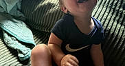 Truett joined the competition — help win amazing prizes! toddler, child, laughing, smiling, indoor, couch, blanket, clothing, nike_logo, happy, person, face, barefoot, shorts, shirt, home, light, texture, seated, cozy