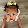 Keemani joined the competition — help win amazing prizes! toddler, child, baby, curly_hair, golden_bow, looking_up, crawling, wooden_floor, indoors, cute, curiosity, skin, face, hands, young_child, pink_clothing, person, portrait, expression, closeup