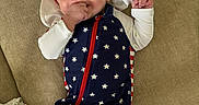 Hunter joined the competition — help win amazing prizes! baby, infant, child, smiling, hat, star_pattern, blue_clothing, red_zipper, white_sleeves, hand_in_mouth, lying_down, beige_background, fabric_texture, cute, happy, portrait, one_person, indoors, casual_clothing, newborn
