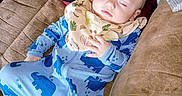 Hunter is registered to the contest to win money with this photo: baby, bib, brown, child, couch, cozy, cute, dinosaur_print, face, hand, indoor, infant, onesie, peaceful, person, pillow, relaxing, sleeping, soft_fabric, toddler