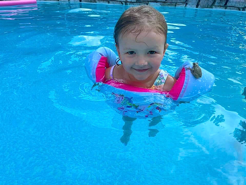Mila is registered to the contest to win money with this photo: aqua, azure, baby, bathing, blue, child, fluid, fun, games, happy, joy, leisure, leisure_centre, liquid, person, personal_protective_equipment, play, recreation, smile, swimming_pool